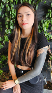 Slender tattooed TukTuk Patrol Rain sits near vines